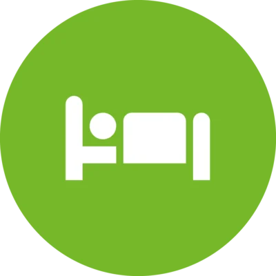 Weißes Piktogramm einer liegenden Person im Bett auf grünem Kreis – symbolisiert Gästewohnung